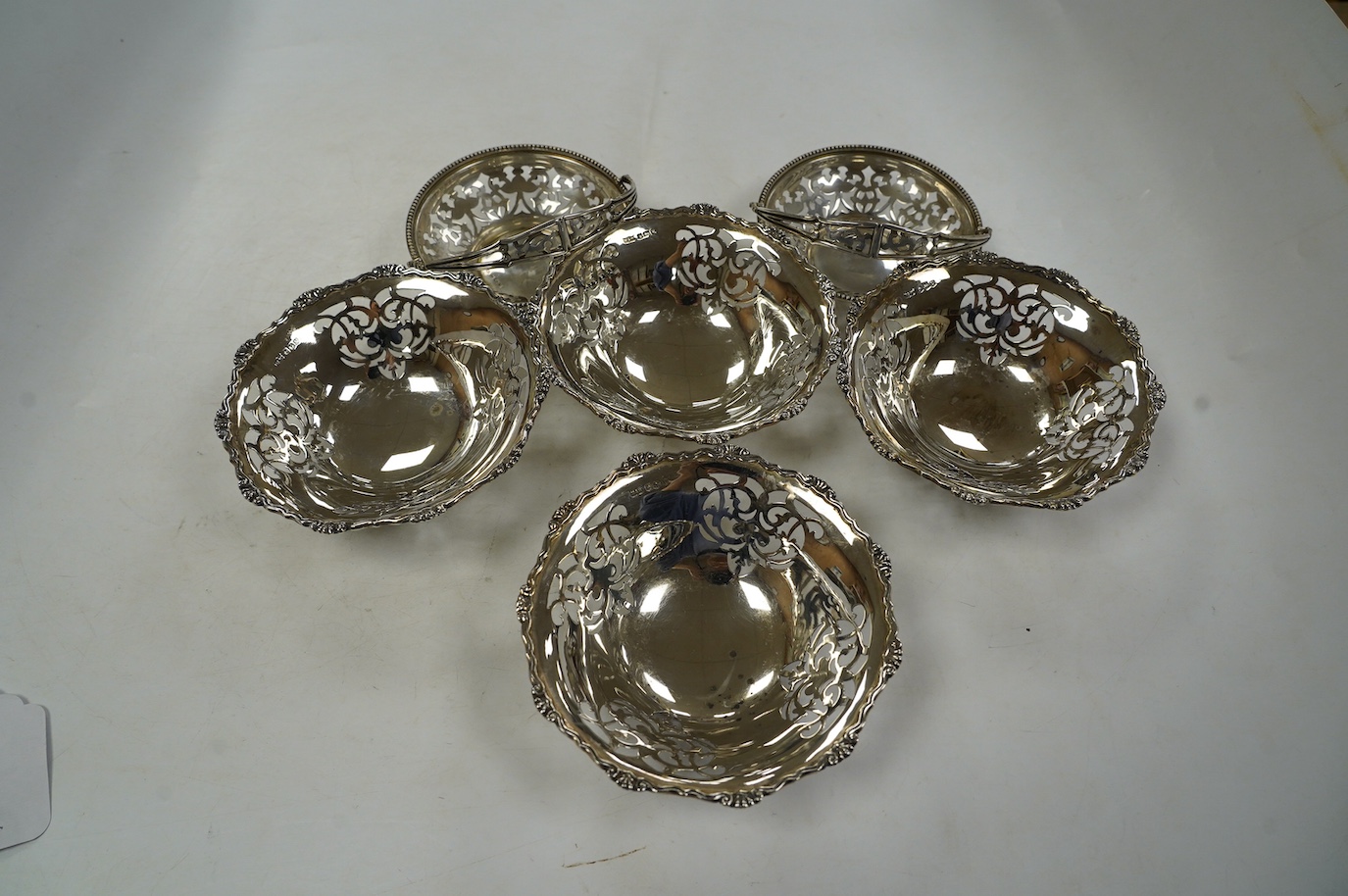 A set of four George VI pierced silver bonbon dishes, by Mappin & Webb, Sheffield, 1938, diameter 12cm and an earlier pair of silver bonbon baskets, 15.7oz. Condition - fair